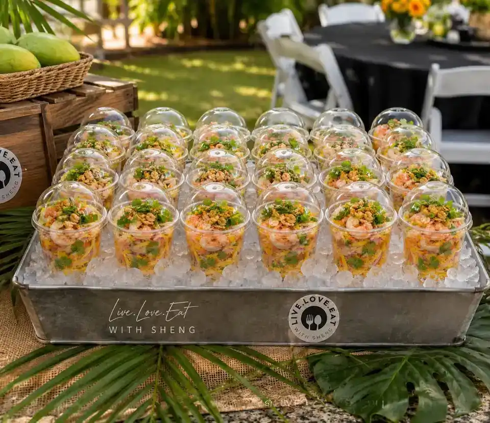 Tray of chilled shrimp mango salad cups on ice at an outdoor event